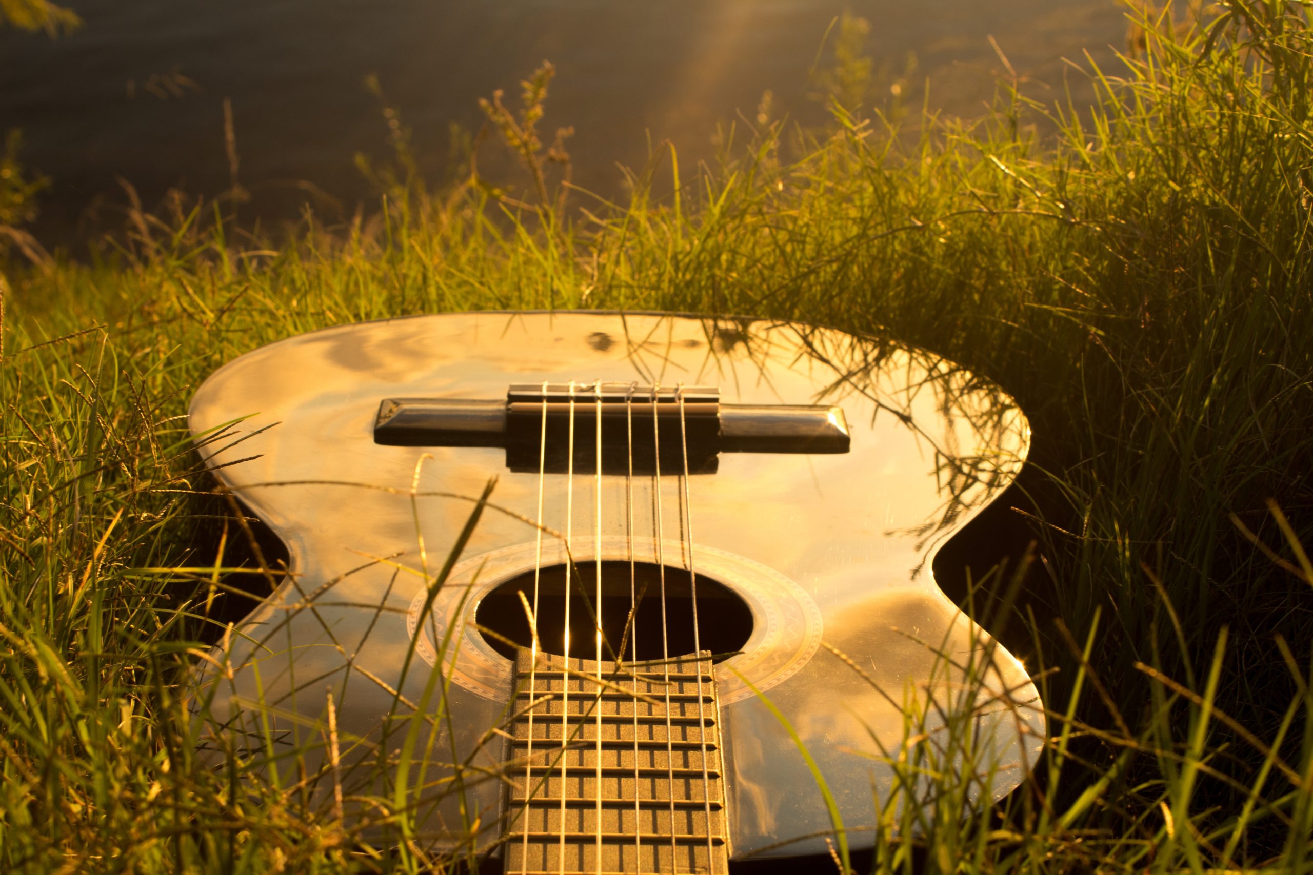 Guitarra sobre la hierba que evoca una sensación de bienestar, como el que consigue la musicoterapia.